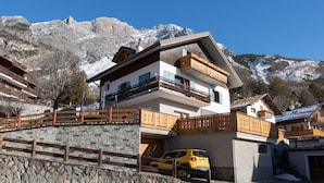 A multi-story chalet with a stone facade, wooden balconies, and a car parked in front. - Italianway - Ripa Fontana 1 Mono (Valdidentro)