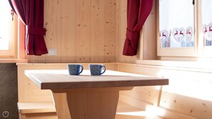 A wooden table with two patterned mugs, a window with curtains, and a wall with a decorative panel.