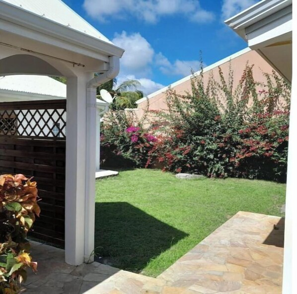 A well-maintained garden with a lawn, a brick wall, and a variety of flowering plants.