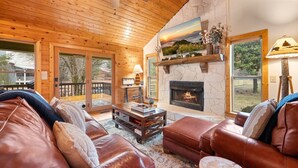 A cozy cabin interior with a stone fireplace, leather sofas, and a wooden ceiling. - Creekfront: Views, Hot Tub, Fire Pit & Game Room (Blue Ridge)