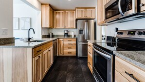 A modern kitchen with wooden cabinets, stainless steel appliances, granite countertops, and a built-in microwave. - Stunning U of O Home – Just Steps from Hayward Field! (Eugene)