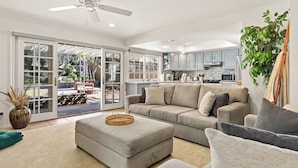 A spacious living room with a grey sofa, a coffee table, and a ceiling fan.