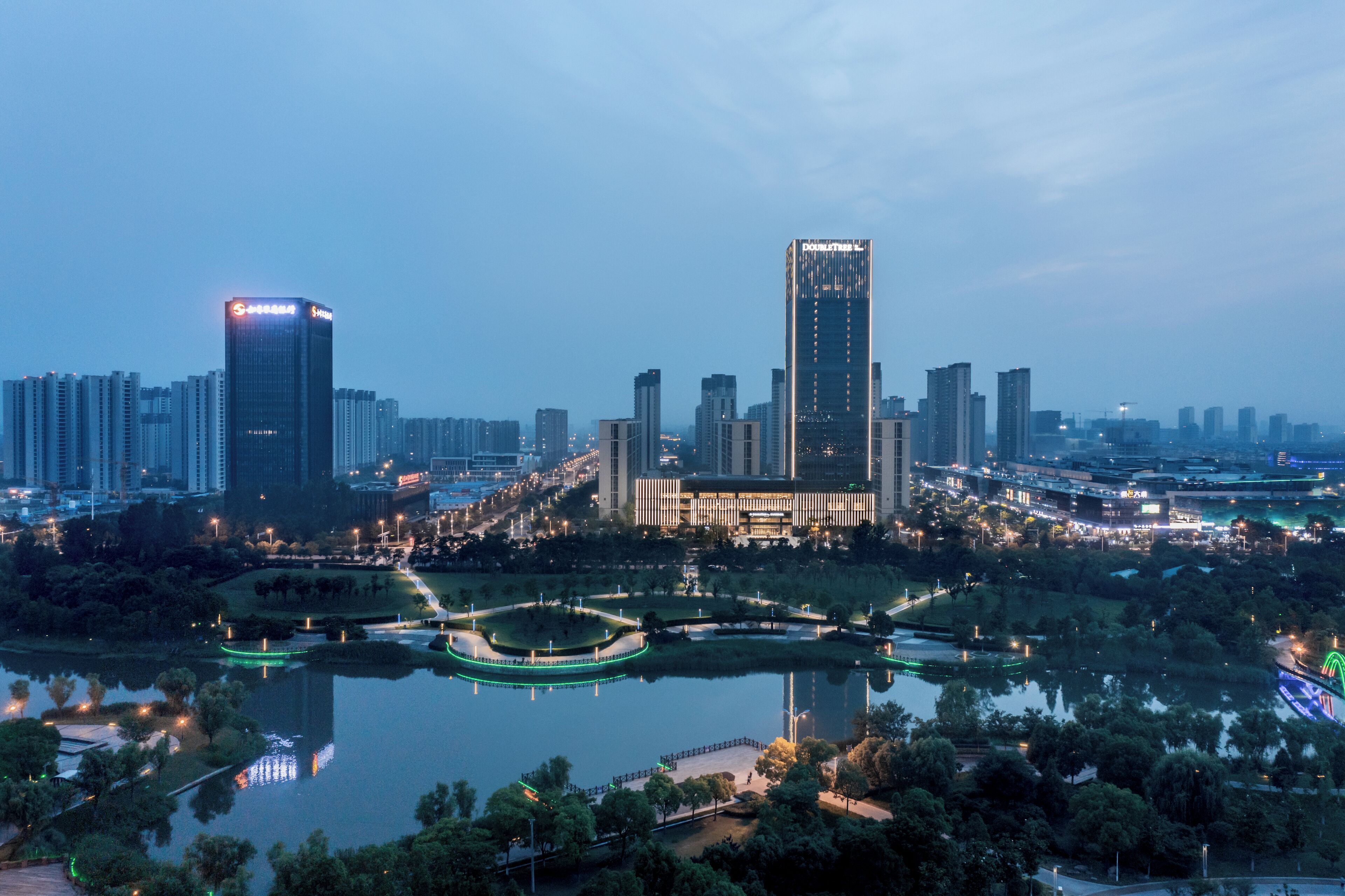 A cityscape with high-rise buildings, a central park with a lake, and surrounding greenery.