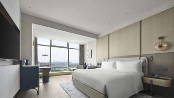 Una habitación de hotel moderna con una cama grande, un escritorio y vistas a la ciudad.