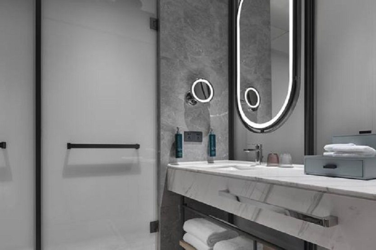 Un baño moderno con tocador de mármol, un espejo grande y un perchero para toallas.