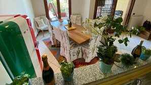 A dining area with a wooden table and chairs, a bottle of wine, and potted plants. - Angiolina apartment in Baveno with terrace (Baveno)