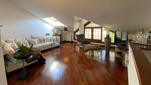 A spacious loft with a high ceiling, wooden flooring, a sofa set, a dining area with a TV, and large windows. - Angiolina apartment in Baveno with terrace (Baveno)