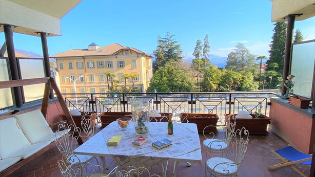 A balcony with a table set for two, surrounded by white metal chairs. - Angiolina apartment in Baveno with terrace (Baveno)