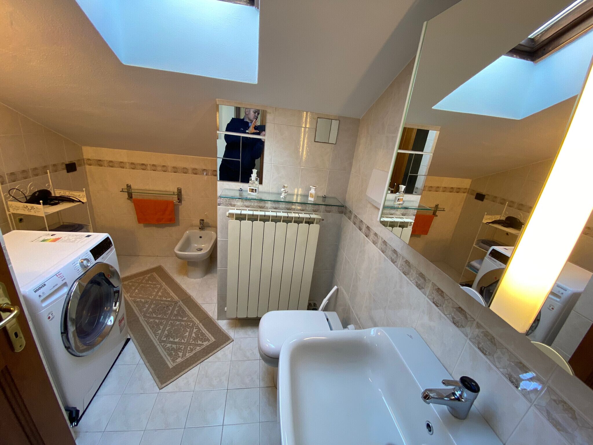 Une salle de bain moderne équipée d’un lave-linge, d’un bidet et d’un grand miroir.