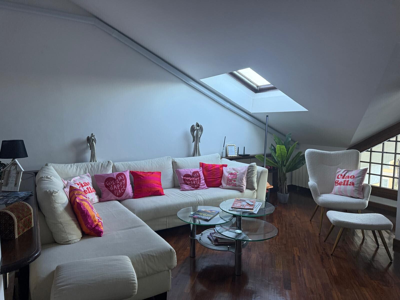 A living room with a sofa, armchairs, a glass coffee table, and a skylight.