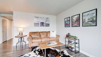 Een woonkamer met een leren bank, een salontafel, een vloerkleed en wanddecoratie.