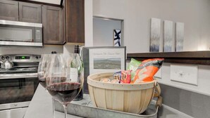 Un comptoir de cuisine avec des verres à vin, un four à micro-ondes, une cuisinière et un bol en bois contenant des collations.