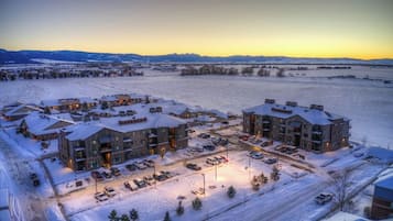 Un barrio residencial con edificios de varios pisos, un estacionamiento y un paisaje cubierto de nieve.