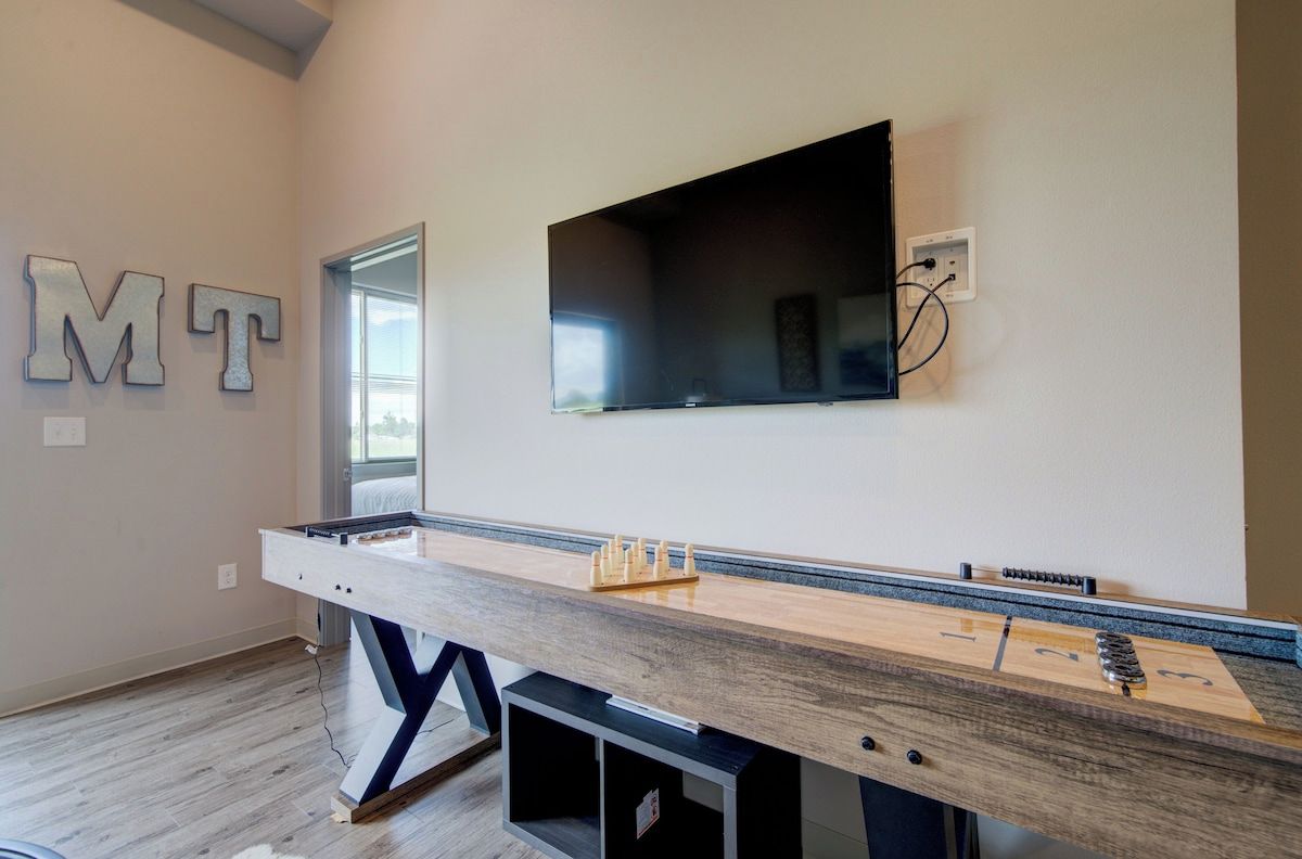 A room with a long wooden table, a mounted TV, and a wall-mounted electrical outlet.