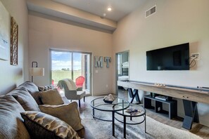 A modern living room with a sofa, coffee table, and a flat-screen TV mounted on the wall. - Yellowstone Country | Mountain Views | Walk to MSU (Bozeman)