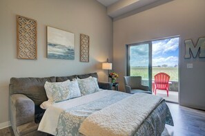 Une chambre avec un grand lit, une table de chevet, une chaise et une vue sur l’extérieur grâce à une porte coulissante.