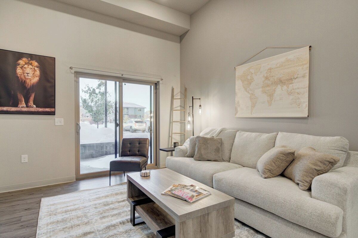 A modern living room with a sofa, a coffee table, a world map, and a lion painting.