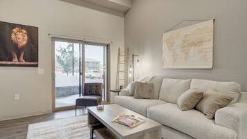 A modern living room with a sofa, a coffee table, a world map, and a lion painting.