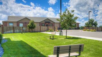 A building with a brick facade, a paved driveway, and a grassy area with a bench.
