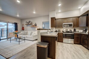 A modern kitchen with a central island, built-in microwave, and stainless steel appliances. - King Bed | Country Music in the Big Sky (Bozeman)