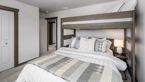 A bedroom with a bunk bed, a bedside table with a lamp, and a door. - Downtown Duplex | Game Room | Mountain Music (Bozeman)