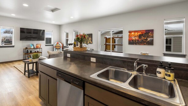 Una cocina moderna con una isla grande, pileta de acero inoxidable y electrodomésticos integrados.