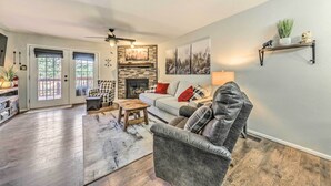 A living room with a fireplace, a sofa, a coffee table, and a bookshelf. - Cozy Ruidoso Condo w/ Grill & Mountain Views! (Ruidoso)