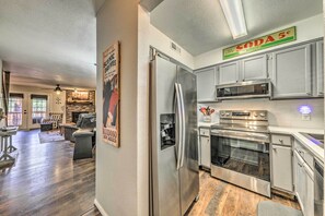 A modern kitchen with stainless steel appliances, a dining area with a fireplace, and a living room with a large window. - Cozy Ruidoso Condo w/ Grill & Mountain Views! (Ruidoso)