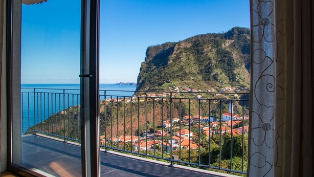Un balcon offrant une vue dégagée sur une ville côtière et une montagne.