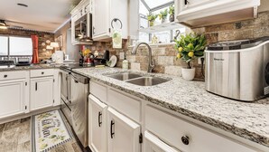 Una cucina moderna con mobili bianchi, piani di lavoro in granito, elettrodomestici in acciaio inossidabile e una finestra vista.