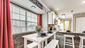 Una cucina con mobili bianchi, un tavolo da pranzo con panche e una finestra con persiane.