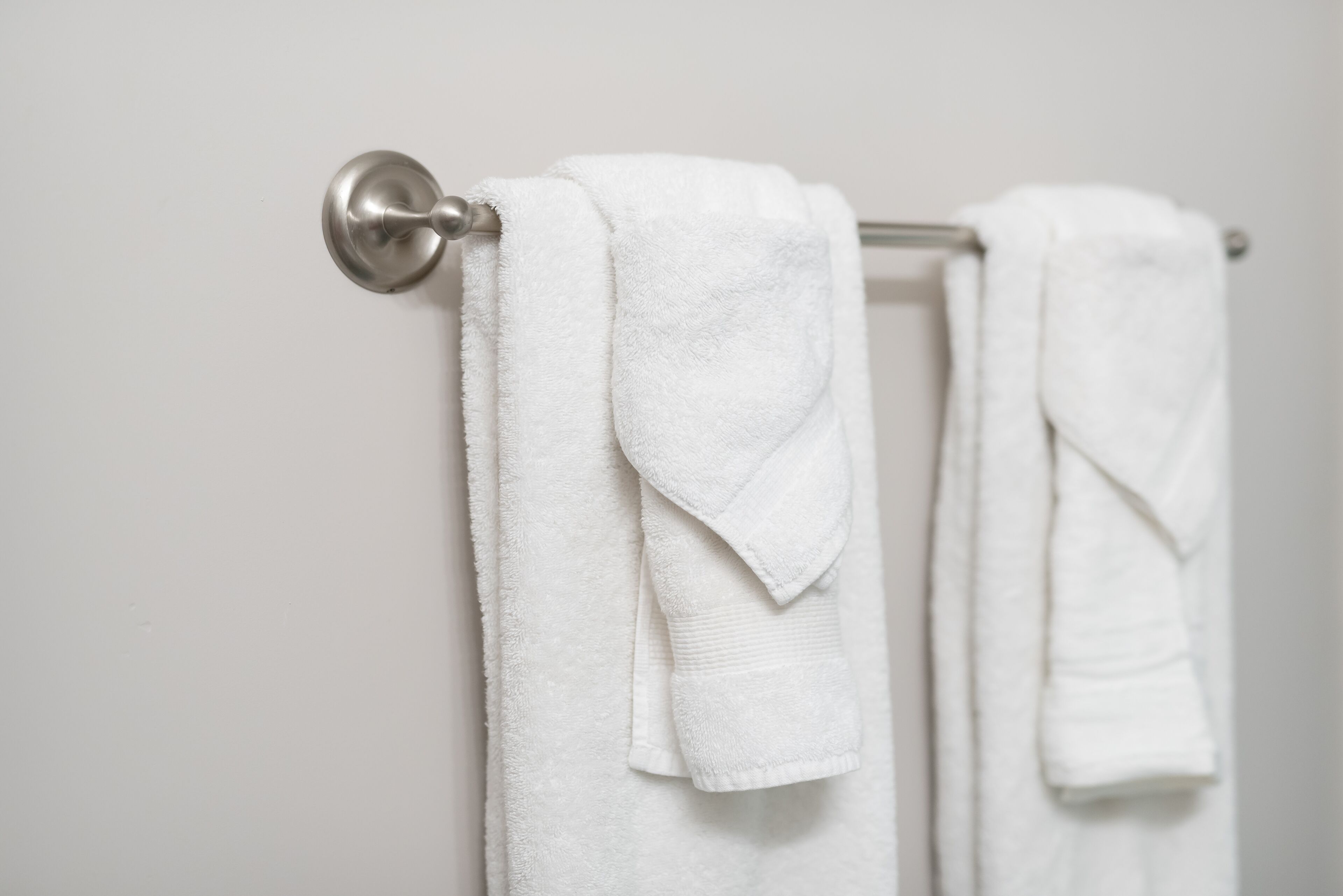 A bathroom with a towel rack holding two white towels.