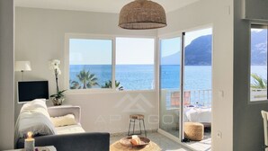 Un soggiorno moderno con una grande finestra vista mare, un divano confortevole, una TV e un'area pranzo con tavolo e sedie.