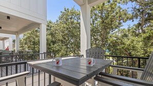 An outdoor patio with a table and chairs, two mugs, and a view of trees. - Sea At Last- Family Fun, Close To Community Pool! (Gulf Shores)