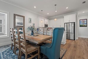 A modern kitchen with white cabinets, stainless steel appliances, and a wooden dining table with chairs.