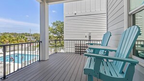 A covered outdoor area with a pool, two Adirondack chairs, and a view of the pool area. - Sea At Last- Family Fun, Close To Community Pool! (Gulf Shores)