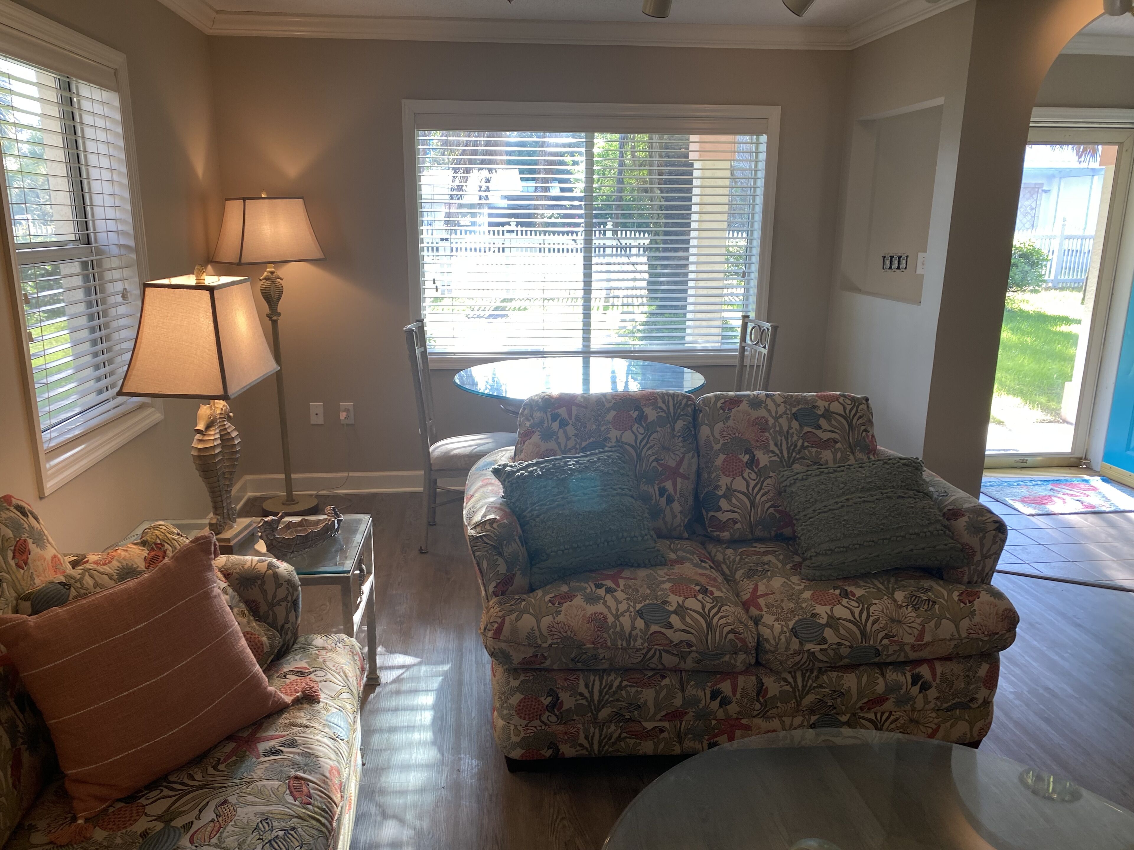 A living room with a floral sofa, a glass coffee table, and a lamp.