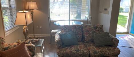 A living room with a floral sofa, a glass coffee table, and a lamp.