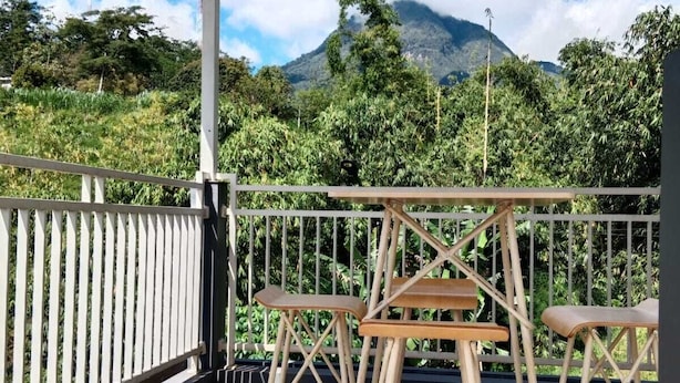 A covered outdoor area with a table and two chairs, surrounded by a white fence and lush greenery. - Azzima villa  (Batu)