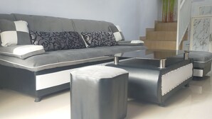 A modern living room with a grey sofa, patterned cushions, and a glass coffee table. - Azzima villa  (Batu)