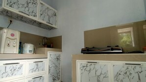 A kitchen with marble-patterned cabinets, a water dispenser, a microwave, and a gas stove. - Azzima villa  (Batu)