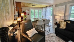 Ein gemütliches Wohnzimmer mit einer schwarzen Ledersofa, einem Essbereich mit Tisch und Stühlen sowie einer Küche im Hintergrund.