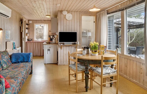 A cozy cabin interior with a dining area, kitchen, and a sofa.
