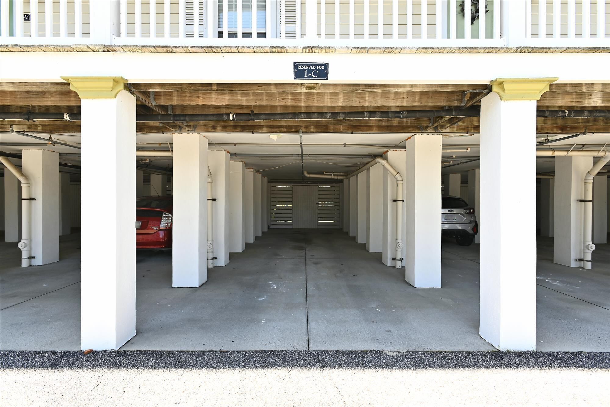 A parking garage with white pillars and a sign indicating reserved parking for 1-C.