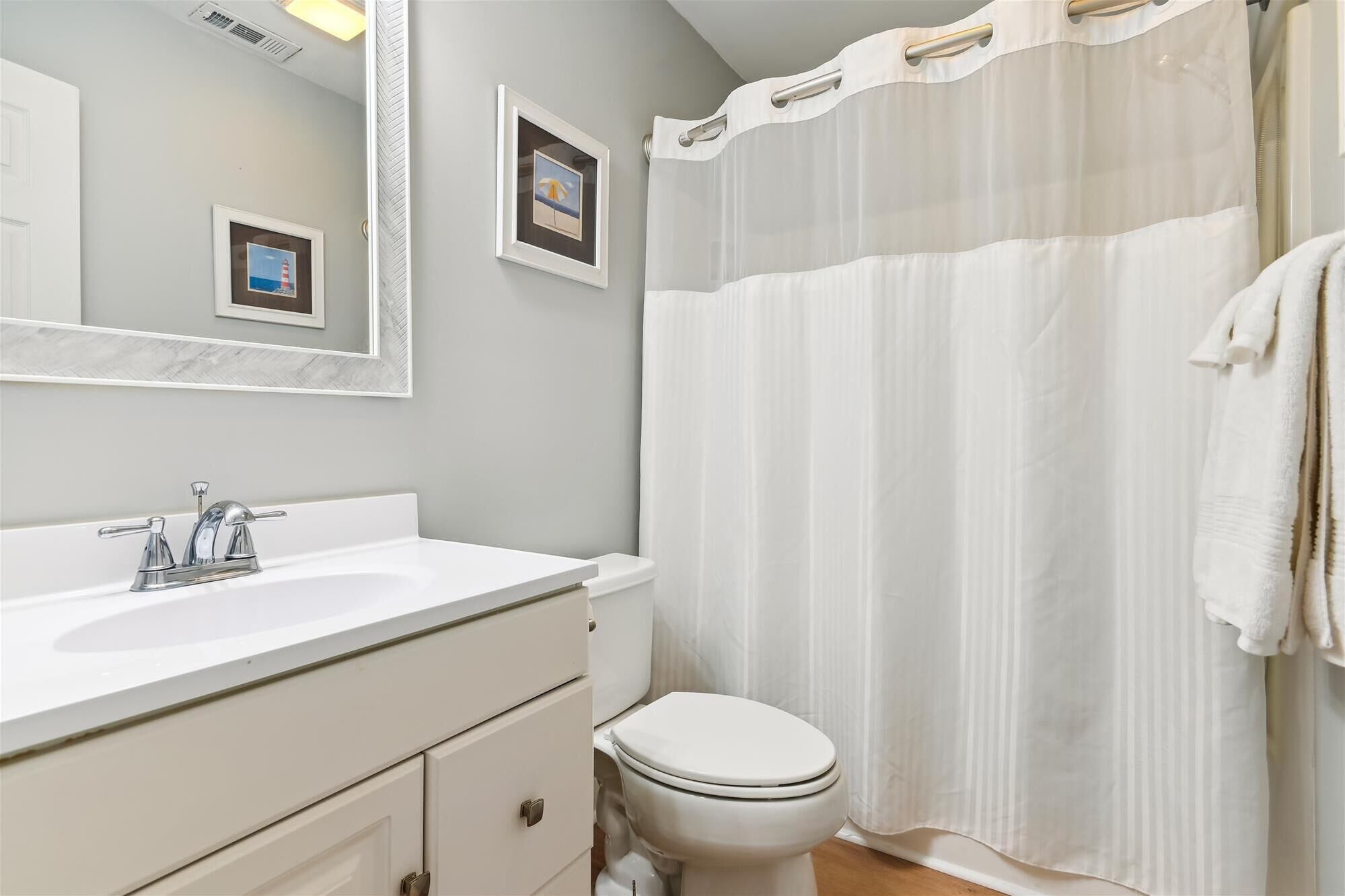 Un baño con lavamanos blanco, inodoro y cortina de ducha.