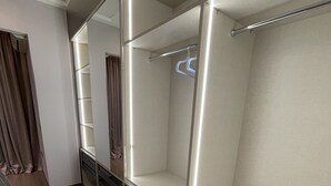 A modern, empty walk-in closet with built-in lighting and a metal rod for hanging clothes. - MAK Apartments (Tirana)