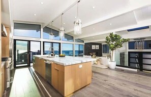 A modern kitchen with a large island, large windows, and a view of the city.