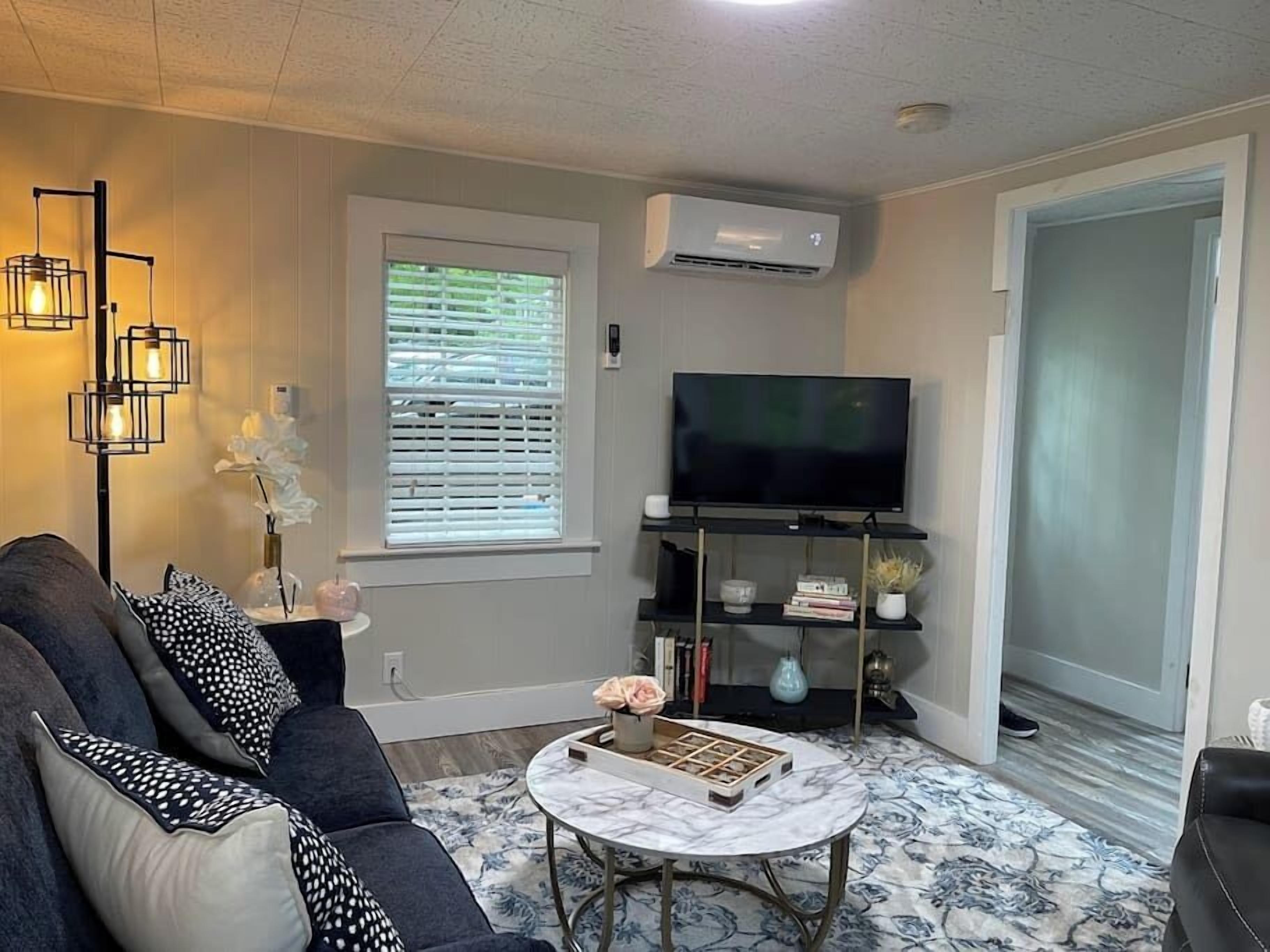 A living room with a sofa, a coffee table, a TV, and a window with blinds.