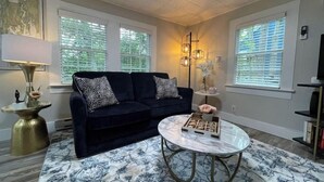 A living room with a dark blue sofa, a round coffee table, and a patterned rug. - Spacious 1 Bedroom Close to Everything 4 (Edgecomb)