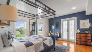 A bedroom with a four-poster bed, a dresser, a television, and a large window with a view of greenery. - Luxurious Estate, Private Heated pool! (West Harwich)